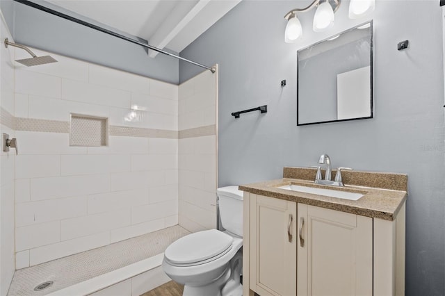 bathroom with a tile shower, vanity, and toilet