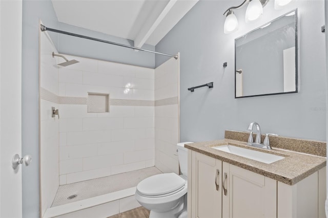 bathroom with vanity, toilet, and a tile shower