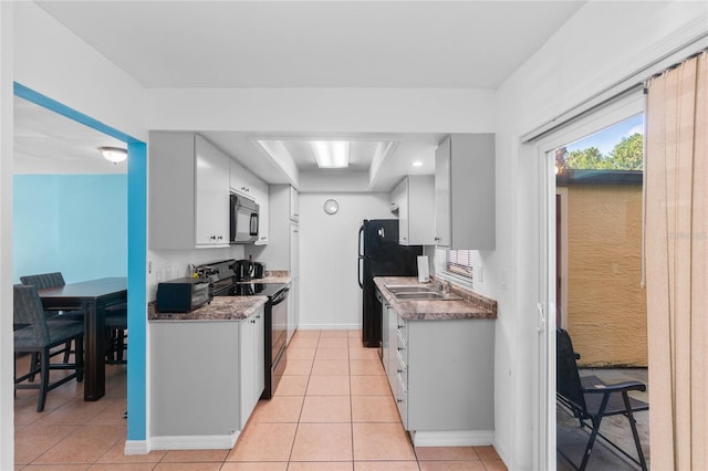 kitchen featuring white cabinets, sink, light tile patterned floors, and black appliances