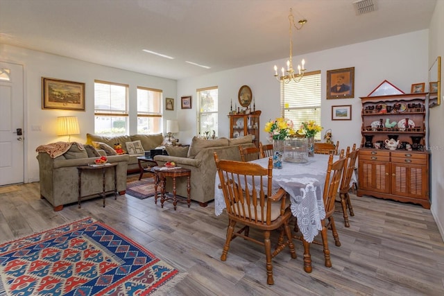 dining space with an inviting chandelier and light hardwood / wood-style flooring