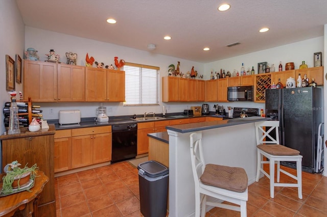 kitchen featuring sink, a kitchen bar, light tile patterned floors, a kitchen island, and black appliances