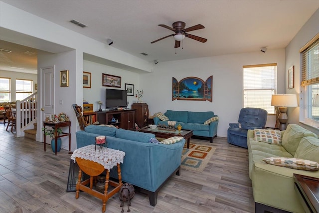 living room with light hardwood / wood-style floors, ceiling fan, and plenty of natural light