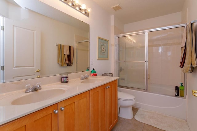 full bathroom featuring toilet, enclosed tub / shower combo, tile patterned floors, and vanity