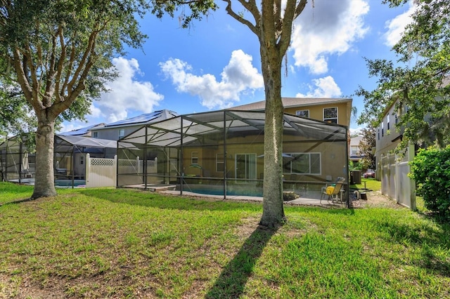 rear view of house with a lanai and a yard