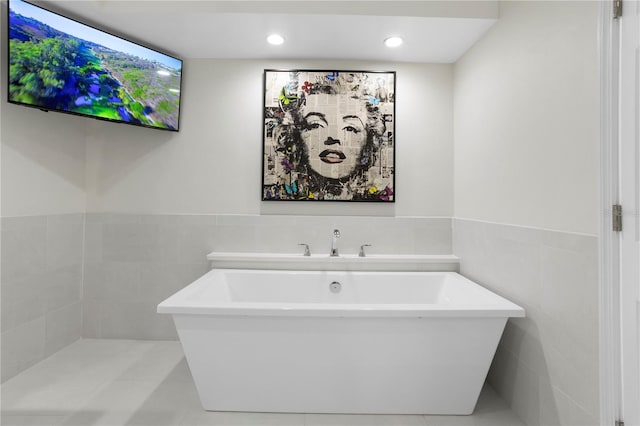 bathroom featuring a bathing tub, tile patterned flooring, and tile walls