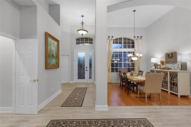 entrance foyer with a towering ceiling, light hardwood / wood-style floors, and an inviting chandelier