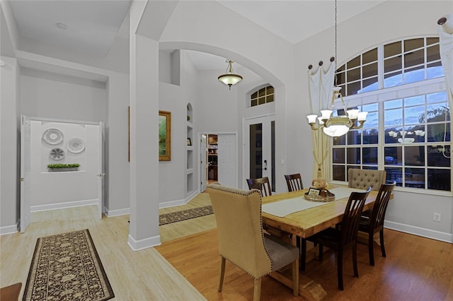 dining area featuring hardwood / wood-style flooring, a notable chandelier, and a high ceiling