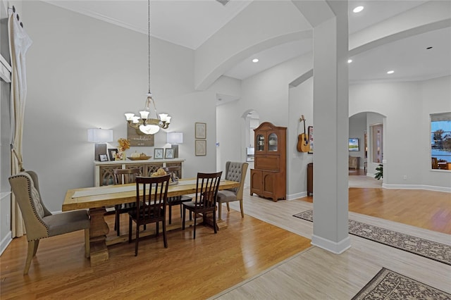 dining space featuring light hardwood / wood-style floors, high vaulted ceiling, and an inviting chandelier