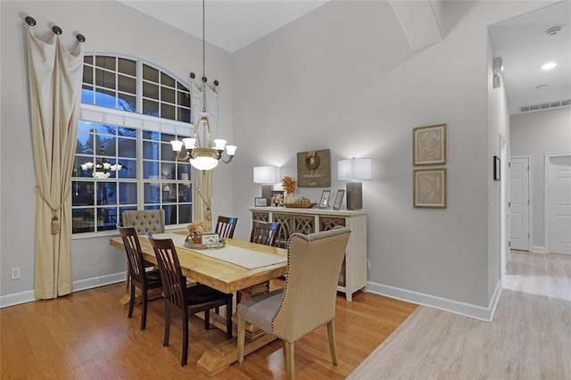 dining space featuring a high ceiling, a notable chandelier, and hardwood / wood-style flooring