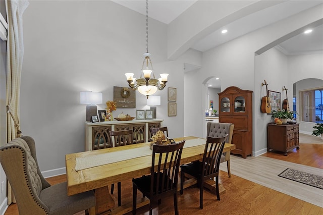 dining space with an inviting chandelier, a high ceiling, and light wood-type flooring