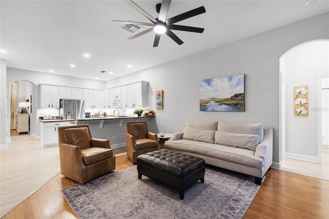 living room with ceiling fan, sink, and light hardwood / wood-style flooring