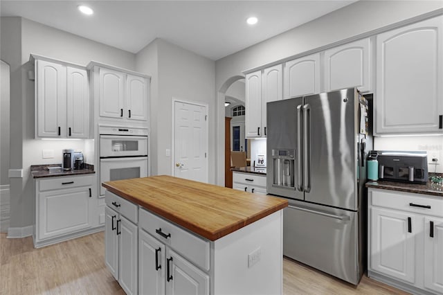 kitchen featuring white cabinetry, stainless steel fridge with ice dispenser, double oven, and light hardwood / wood-style floors