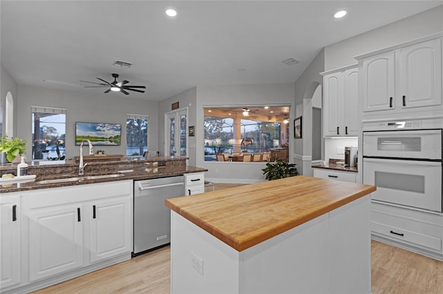 kitchen featuring white cabinets, stainless steel dishwasher, double oven, and sink