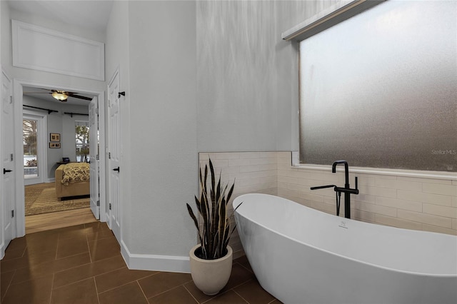 bathroom with tile patterned floors, ceiling fan, a tub, and tile walls