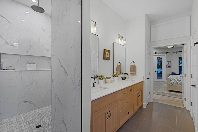 bathroom featuring tile patterned flooring, a tile shower, and vanity