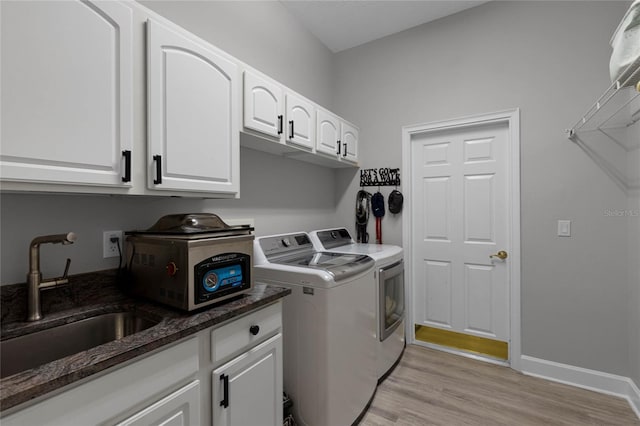 clothes washing area featuring light hardwood / wood-style floors, cabinets, sink, and washing machine and dryer