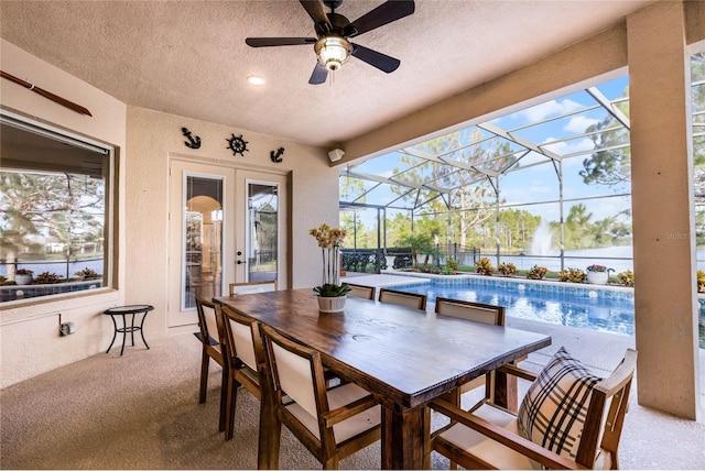 view of patio with a lanai, ceiling fan, and a water view