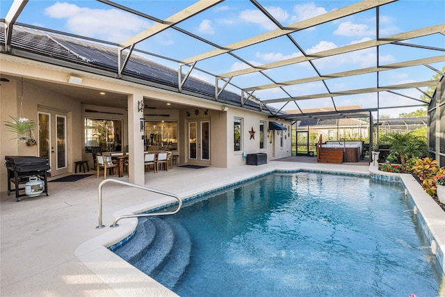 view of pool with glass enclosure, a patio, and a hot tub