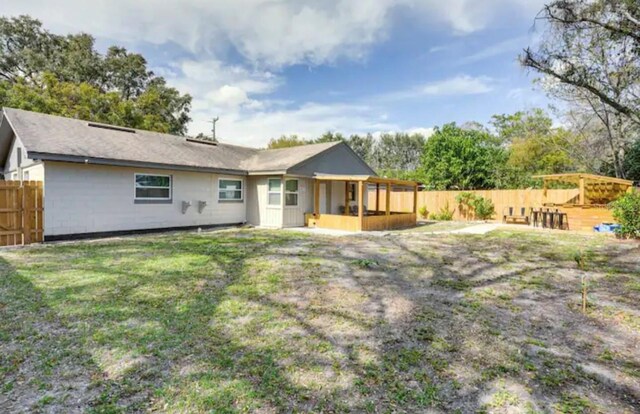 rear view of house with a lawn and a sunroom