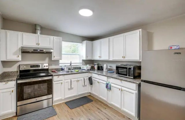 kitchen featuring sink, light stone countertops, light hardwood / wood-style floors, white cabinetry, and stainless steel appliances