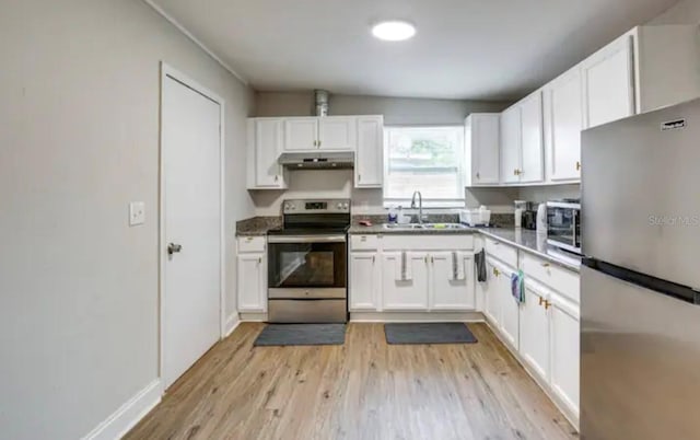 kitchen with appliances with stainless steel finishes, light wood-type flooring, vaulted ceiling, sink, and white cabinets