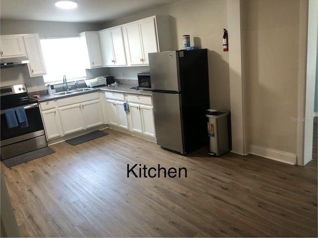 kitchen with appliances with stainless steel finishes, sink, hardwood / wood-style flooring, white cabinetry, and lofted ceiling