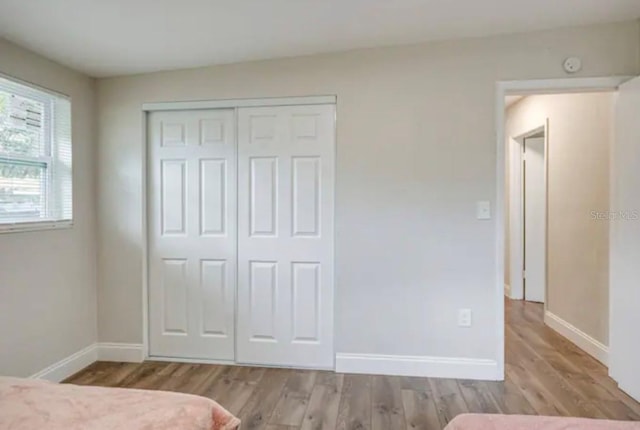 unfurnished bedroom with light wood-type flooring and a closet