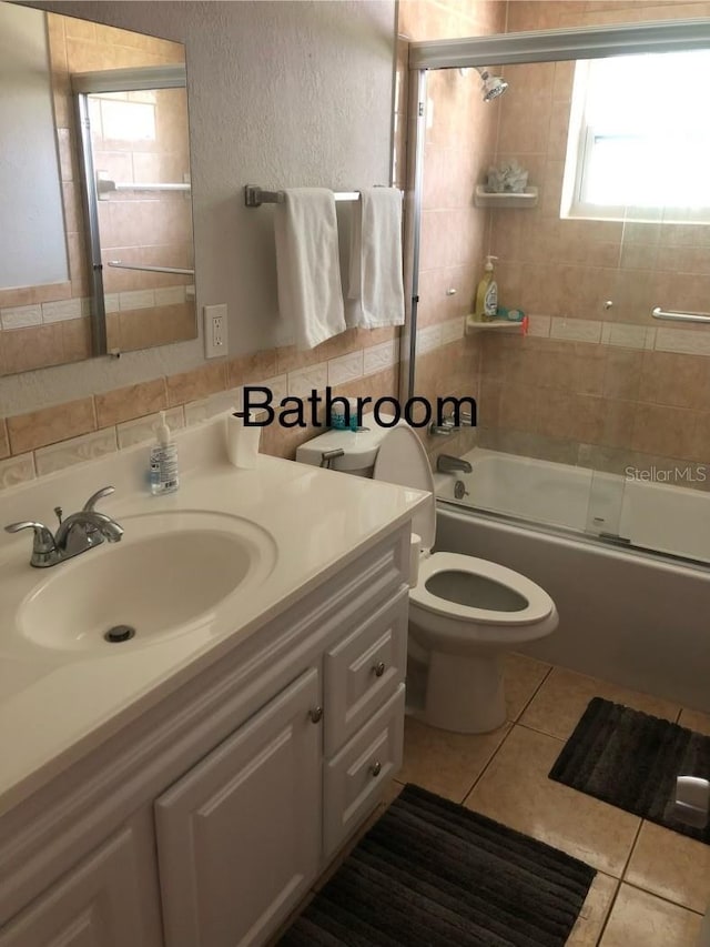 full bathroom featuring combined bath / shower with glass door, vanity, tile patterned flooring, and toilet