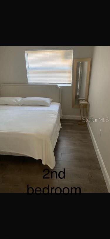 unfurnished bedroom with dark wood-type flooring and multiple windows