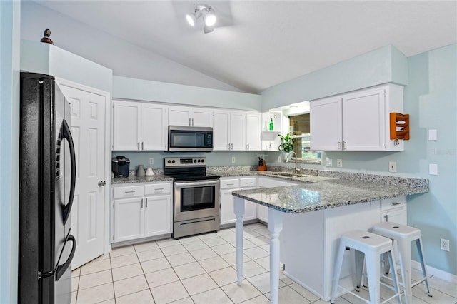 kitchen featuring vaulted ceiling, a breakfast bar area, kitchen peninsula, stainless steel appliances, and light stone counters