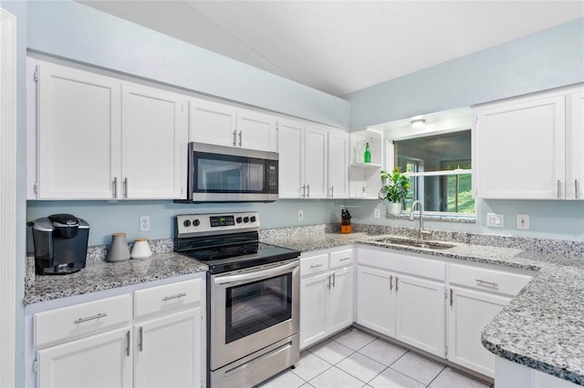 kitchen with white cabinets, sink, light tile patterned floors, stainless steel appliances, and light stone counters