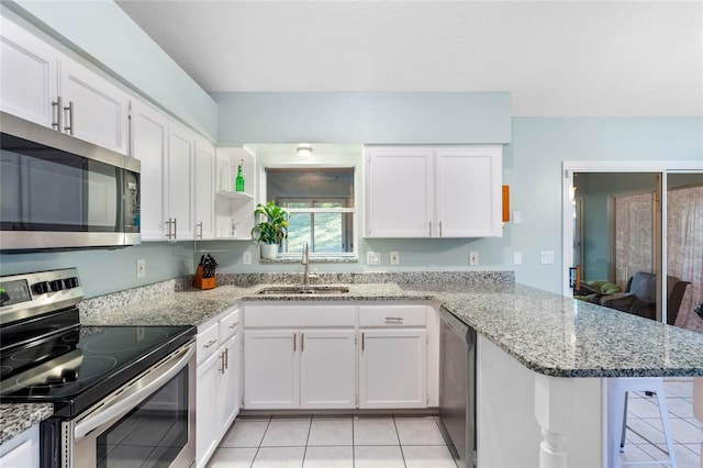 kitchen with white cabinetry, sink, appliances with stainless steel finishes, light tile patterned floors, and kitchen peninsula