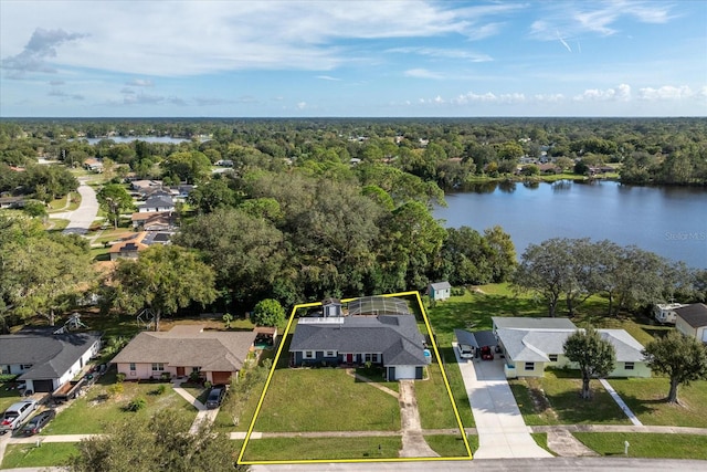 drone / aerial view featuring a view of trees, a water view, and a residential view