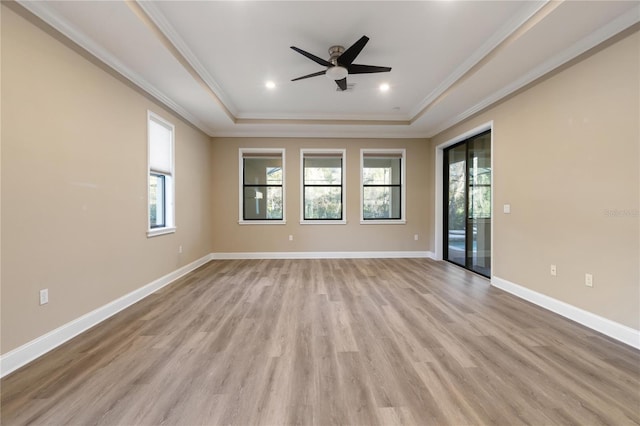 spare room featuring ornamental molding, light hardwood / wood-style floors, ceiling fan, and a tray ceiling