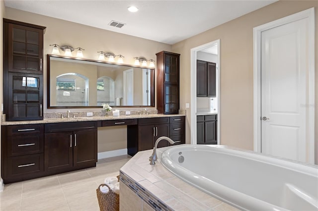 bathroom with tile patterned flooring, vanity, and tiled bath