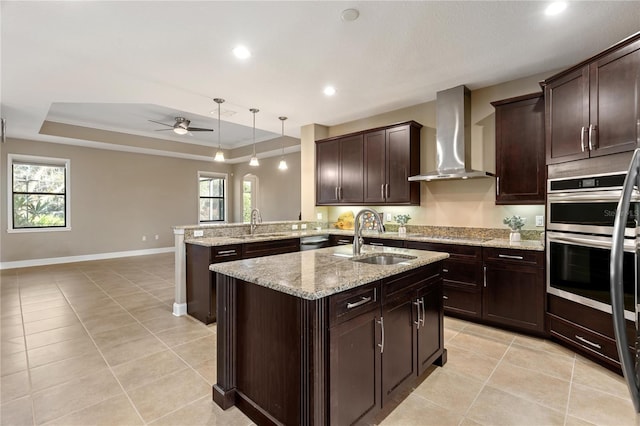 kitchen featuring kitchen peninsula, sink, a wealth of natural light, and wall chimney range hood