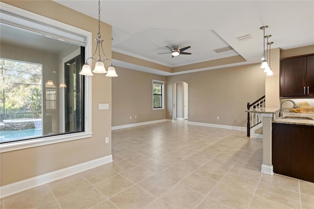 interior space with ornamental molding, light stone counters, a healthy amount of sunlight, and sink