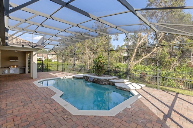 view of pool with glass enclosure, exterior kitchen, grilling area, pool water feature, and a patio