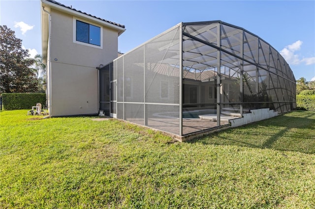 rear view of house with glass enclosure, a patio area, and a yard