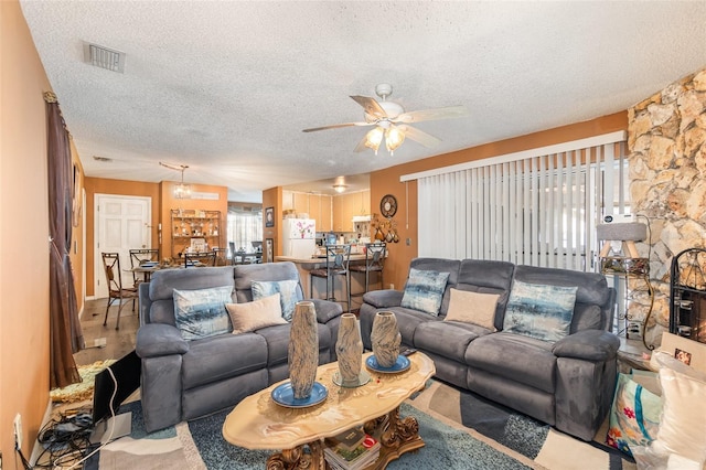 living room featuring ceiling fan and a textured ceiling