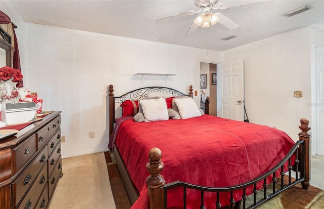 bedroom featuring light carpet, ceiling fan, and a textured ceiling