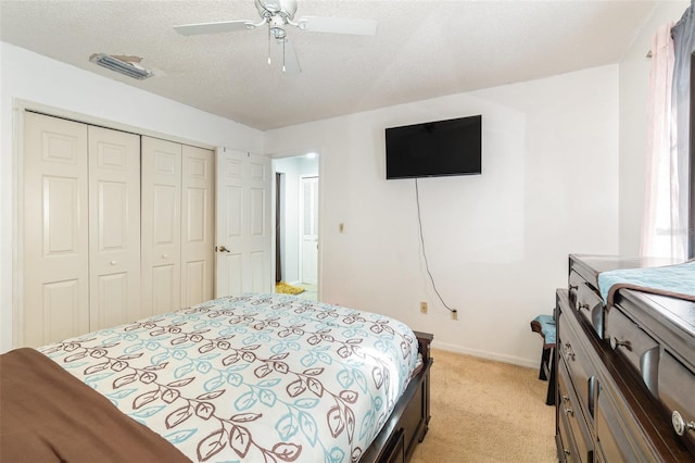 bedroom featuring light carpet, a textured ceiling, a closet, and ceiling fan