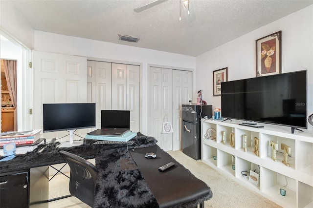 office area featuring a textured ceiling, light colored carpet, and ceiling fan