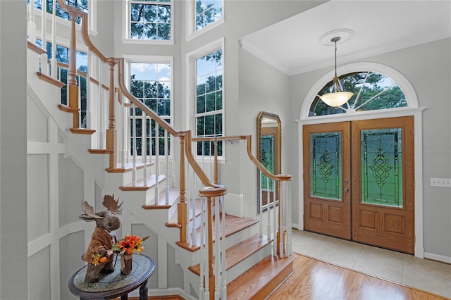 entrance foyer featuring a wealth of natural light, light hardwood / wood-style flooring, french doors, and ornamental molding