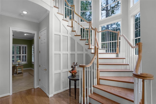 stairs featuring wood-type flooring and ornamental molding