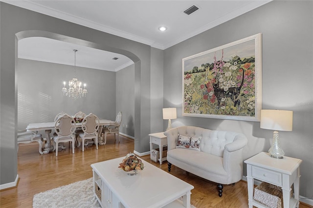 living room featuring hardwood / wood-style flooring, a chandelier, and ornamental molding