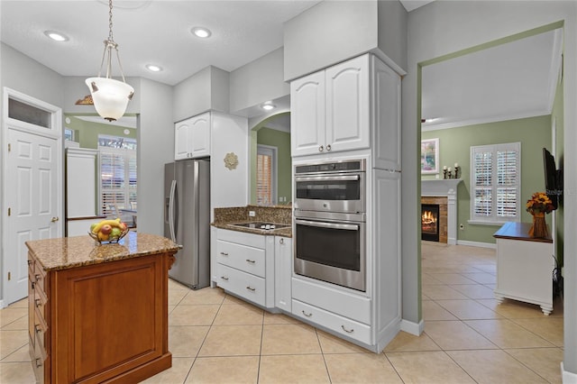 kitchen with white cabinets, appliances with stainless steel finishes, pendant lighting, and crown molding