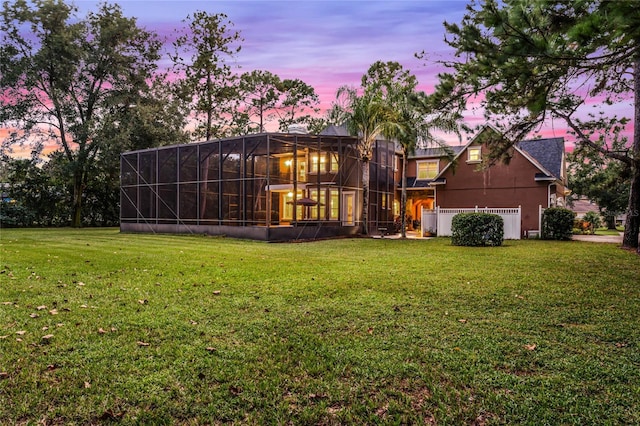 back house at dusk featuring a lawn