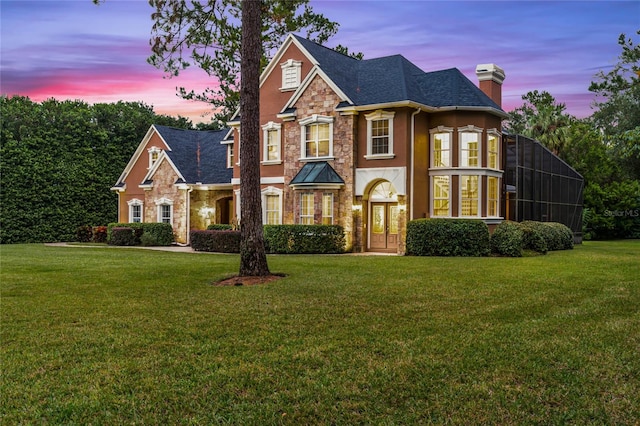 view of front facade with a lawn and glass enclosure