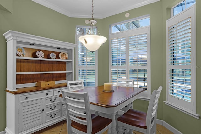 tiled dining room with crown molding and baseboards